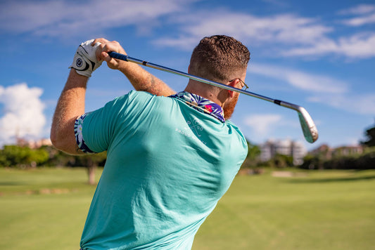 Golfer in turquoise shirt following through on a swing at a sunny course illustrating how to start golfing for beginners