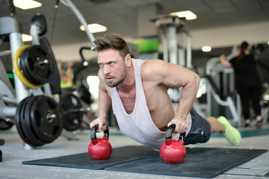 Man performing push-ups using kettlebells in a gym during a beginner kettlebell workout