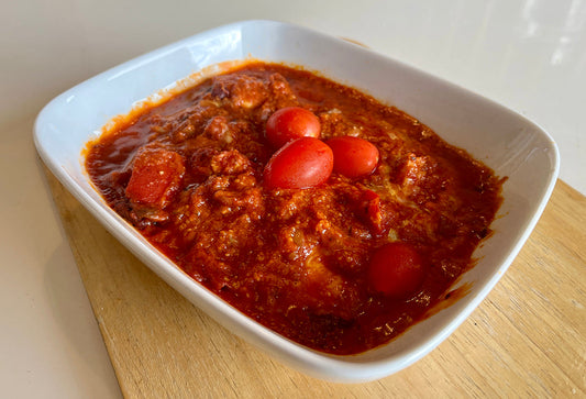 Delicious high protein Mexican chicken recipe with vibrant red sauce and cherry tomatoes in a white bowl