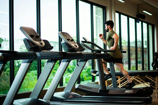 Man running on a treadmill in a gym, perfect for beginner fitness journey tips and motivation