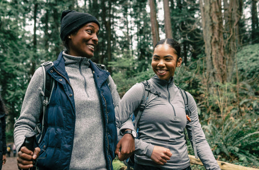Two women smiling while enjoying beginner's power walking tips in a forested area
