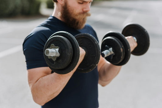 Beginner lifting dumbbells with a focused expression in a friendly outdoor setting for the beginners guide to weight lifting