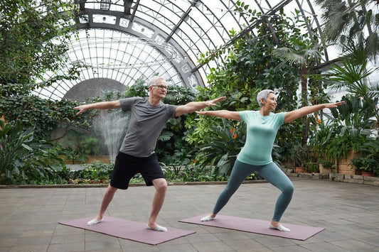 Senior couple practicing yoga in a greenhouse using beginner fitness tips for over 50
