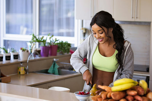 Woman preparing healthy meals in kitchen, emphasizing nutrition for fitness and a balanced diet