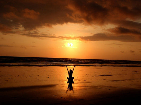 Person meditating on beach at sunset reflecting calm and beginner meditation tips for a relaxing practice