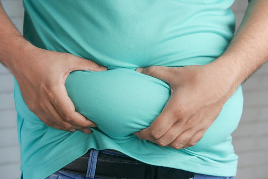 Man squeezing belly fat wearing a teal shirt illustrating beginner's guide to dietary fat