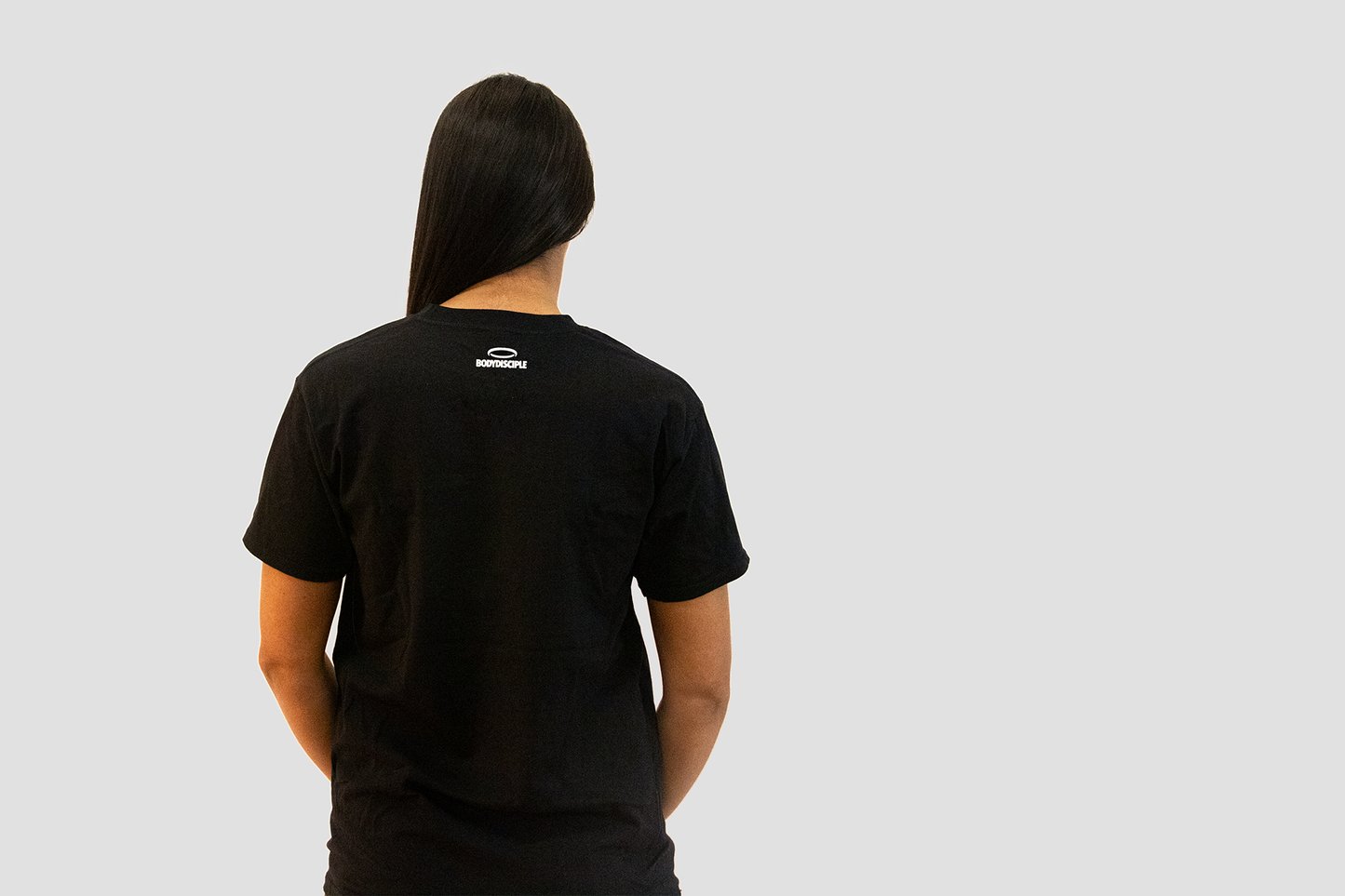 Back view of a durable gym tee for women by BodyDisciple in black fabric