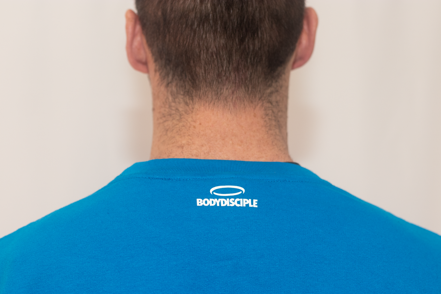 Men's sapphire sweatshirt by BodyDisciple featuring a simple logo design on the back