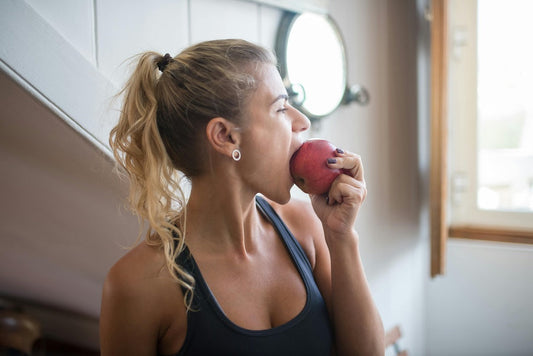 Woman enjoying a red apple while emphasizing the benefits of meal planning for beginners