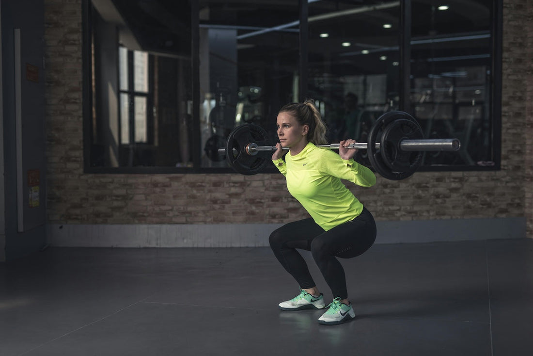 Woman performing squats with a barbell, showcasing the benefits of lifting weights for beginners