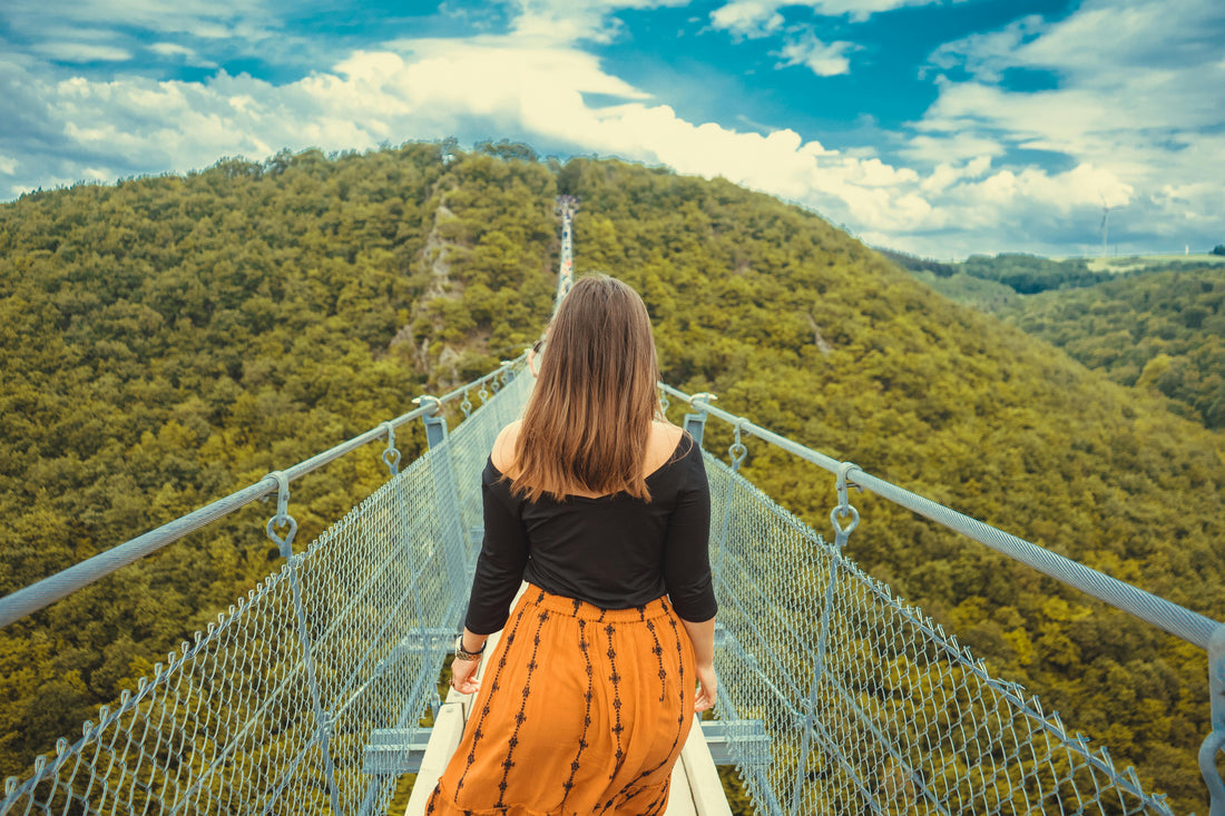 Woman walking on a bridge surrounded by greenery, showcasing health benefits of walking daily