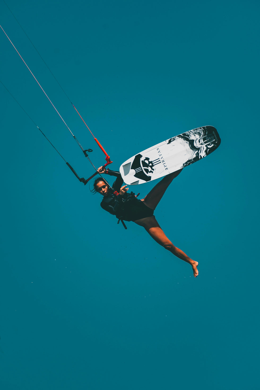 Kiteboarder soaring in the air during a kite surfing session in clear blue skies