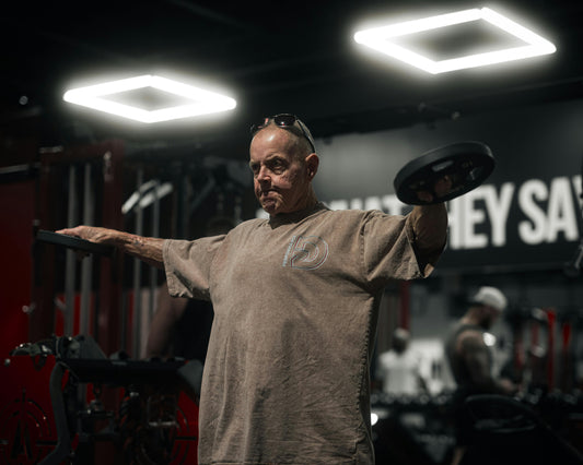 Older man exercising with weights in a gym, emphasizing fitness for those in their 50s