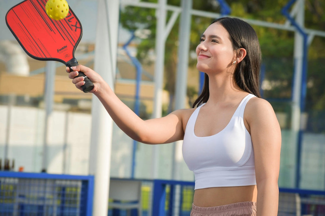 Beginner pickleball guide showcasing a woman practicing her serve with a paddle outdoors