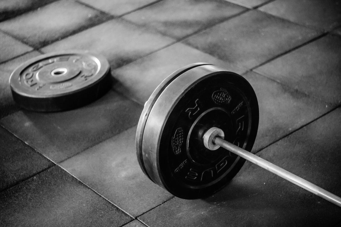 Barbell and weights on gym floor representing how to start getting fit at 50
