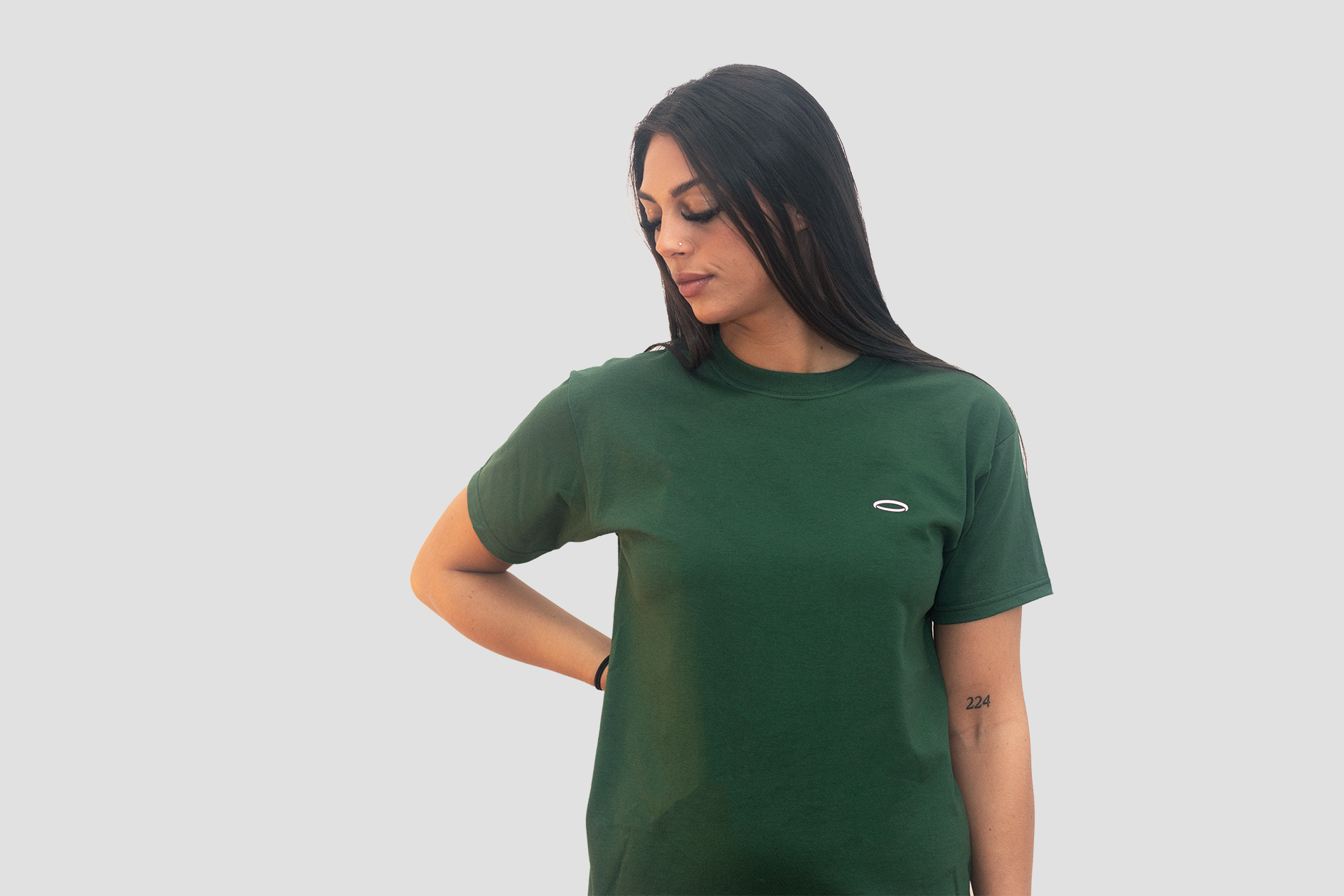 A woman, looking down, wearing Bodydisciple green tee B24D301GRN_Womens_2