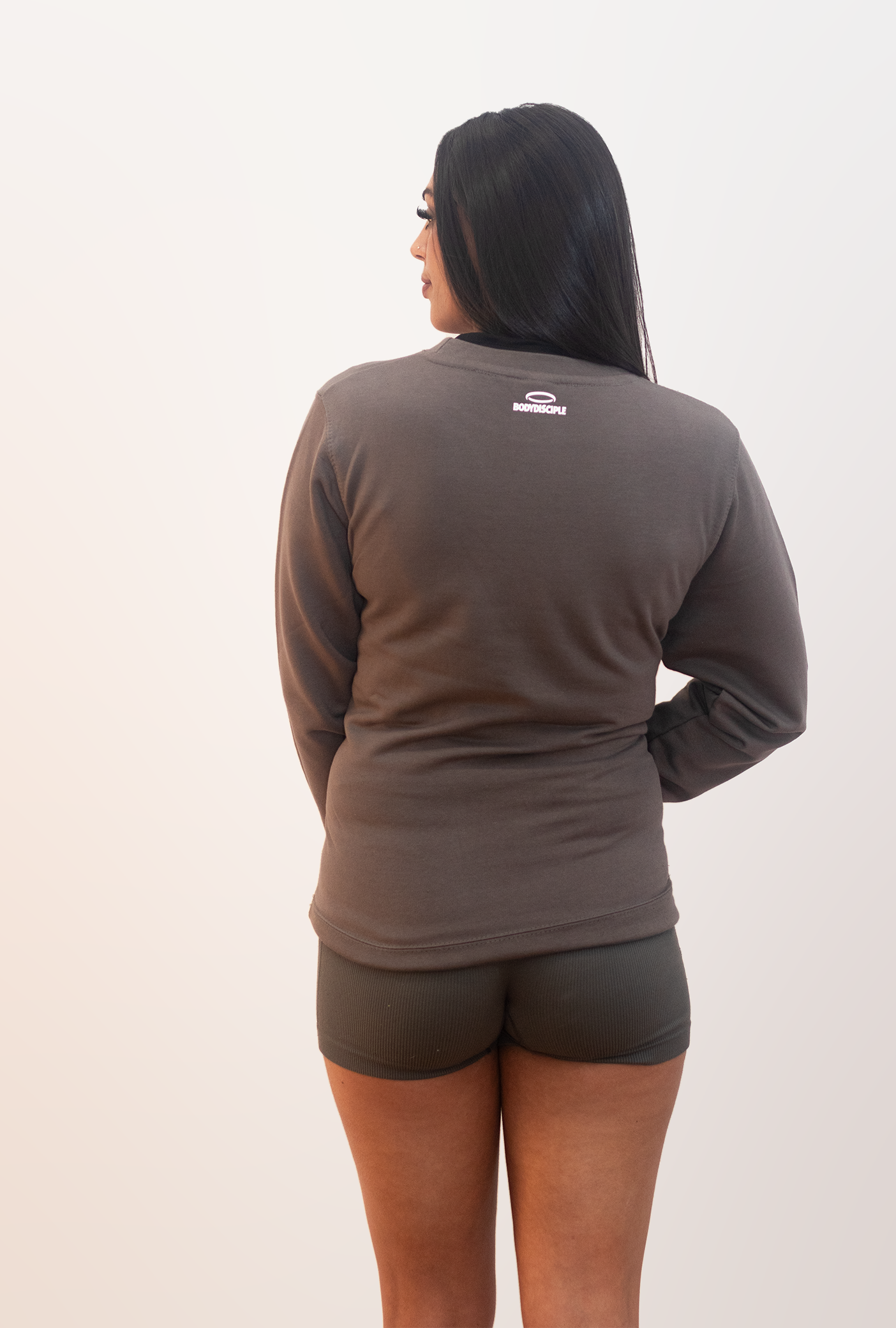 Back view of a woman wearing a stone colored sweatshirt, perfect for casual and comfortable styling.